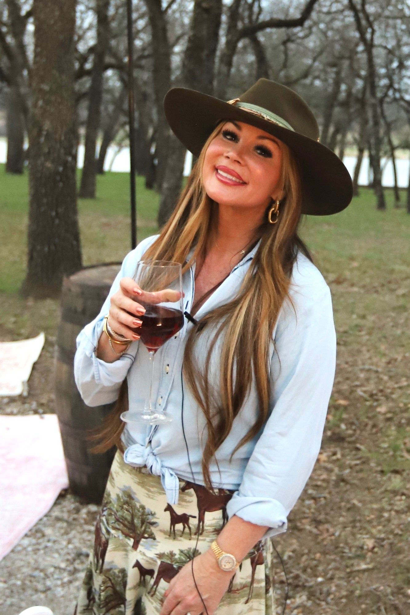 Jenn at sunset in a Hill Country oak grove, holding a glass of red wine.